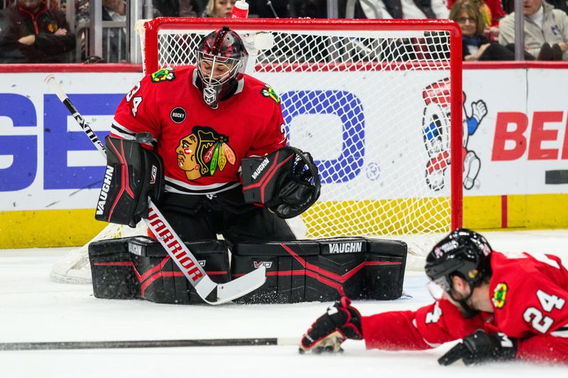 Feb 9, 2024; Chicago, Illinois, USA; Chicago Blackhawks goaltender Petr Mrazek (34) makes a save as defenseman Jaycob Megna (24) dives to block the shot against the New York Rangers during the second period at the United Center. Mandatory Credit: Daniel Bartel-USA TODAY Sports