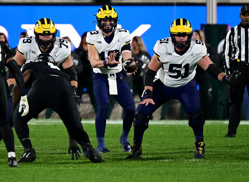 Oct 21, 2023; East Lansing, Michigan, USA;  Michigan Wolverines quarterback Jack Tuttle (13) takes a snap from Michigan Wolverines Greg Crippen (51) in the fourth quarter against the Michigan State Spartans at Spartan Stadium. Mandatory Credit: Dale Young-USA TODAY Sports