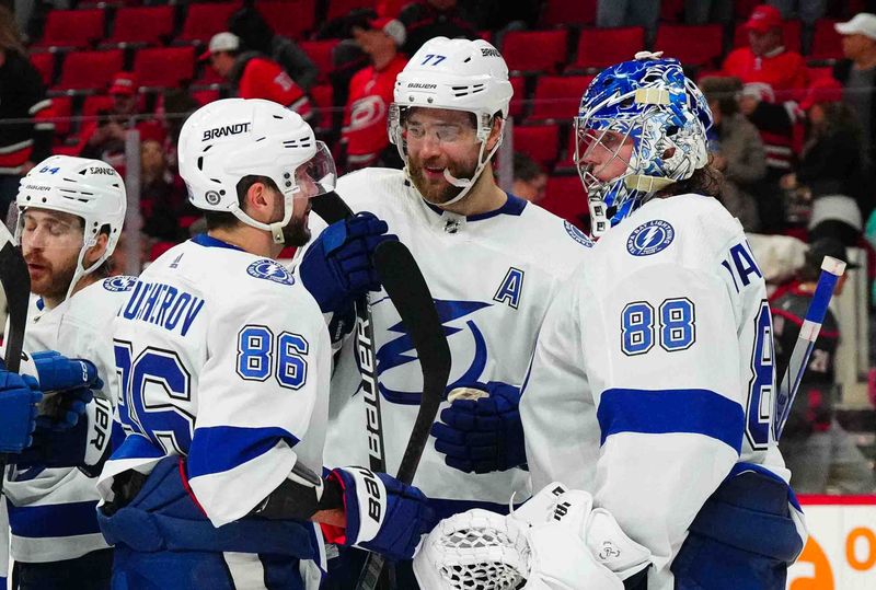 Nov 24, 2023; Raleigh, North Carolina, USA; Tampa Bay Lightning goaltender Andrei Vasilevskiy (88) is congratulated by defenseman Victor Hedman (77) and  right wing Nikita Kucherov (86) after their victory against the Carolina Hurricanes at PNC Arena. Mandatory Credit: James Guillory-USA TODAY Sports