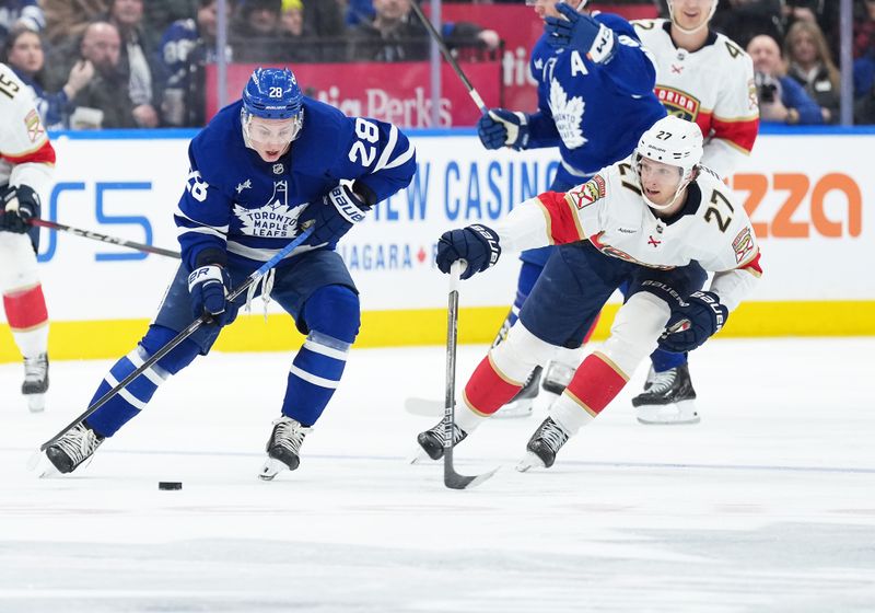 Jan 6, 2026; Toronto, Ontario, CAN; Toronto Maple Leafs defenseman Troy Stecher (28) battles for the puck with Florida Panthers center Eetu Luostarinen (27) during the second period at Scotiabank Arena. Mandatory Credit: Nick Turchiaro-Imagn Images
