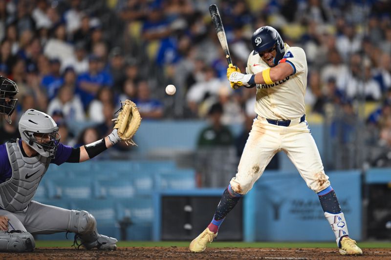 Sep 21, 2024; Los Angeles, California, USA; Los Angeles Dodgers shortstop Miguel Rojas (11) is struck by the ball against Colorado Rockies catcher Jacob Stallings (25) during the sixth inning at Dodger Stadium. Mandatory Credit: Jonathan Hui-Imagn Images