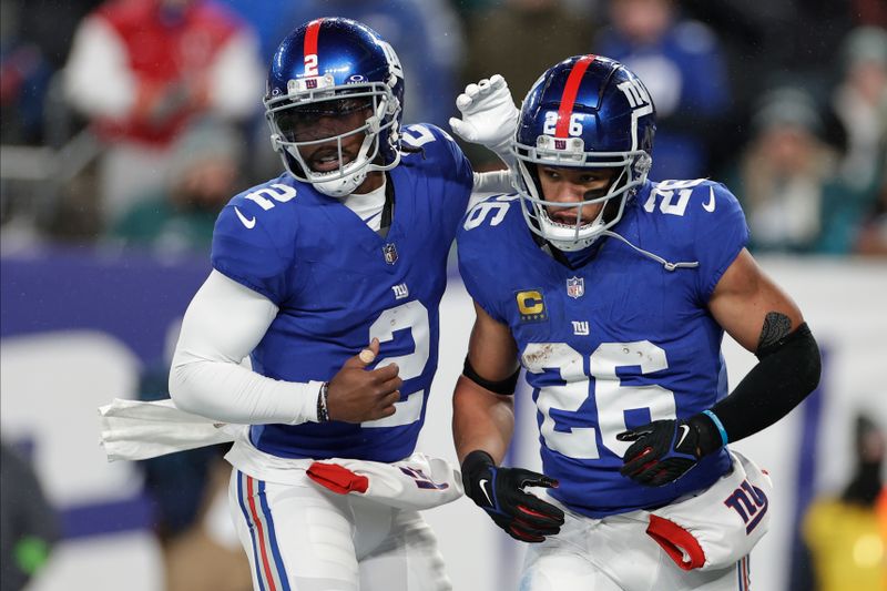 New York Giants running back Saquon Barkley (26) celebrates with quarterback Tyrod Taylor (2) after scoring a touchdown against the Philadelphia Eagles during the first quarter of an NFL football game, Sunday, Jan. 7, 2024, in East Rutherford, N.J. (AP Photo/Adam Hunger)