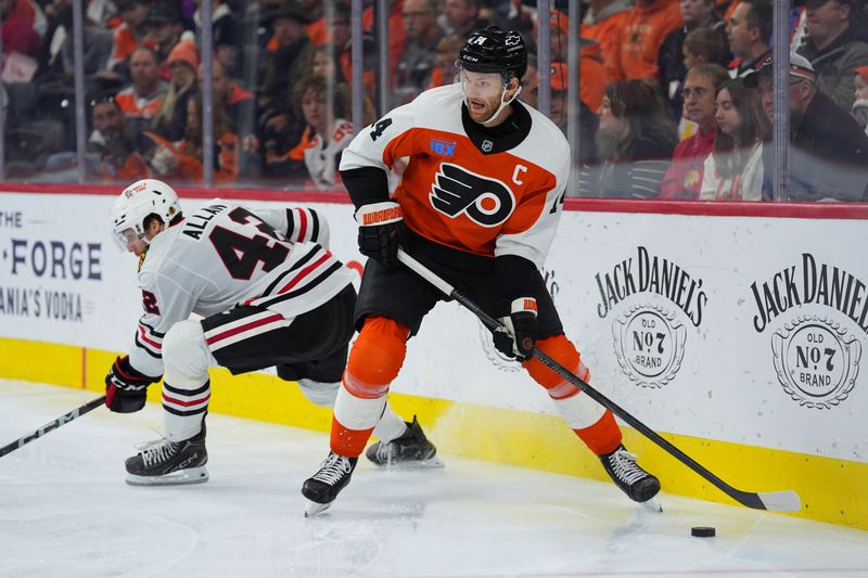 Nov 23, 2024; Philadelphia, Pennsylvania, USA; Philadelphia Flyers center Sean Couturier (14) controls the puck against Chicago Blackhawks defenseman Nolan Allan (42) in the third period at Wells Fargo Center. Mandatory Credit: Kyle Ross-Imagn Images