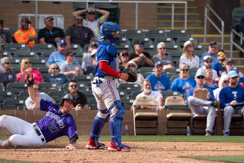 Mar 6, 2024; Salt River Pima-Maricopa, Arizona, USA; Colorado Rockies outfielder Bradley Zimmer (27) slides in to score in the eighth as Texas Rangers catcher Braxton Fulford (71) awaits the ball during a spring training game at Salt River Fields at Talking Stick. Mandatory Credit: Allan Henry-USA TODAY Sports