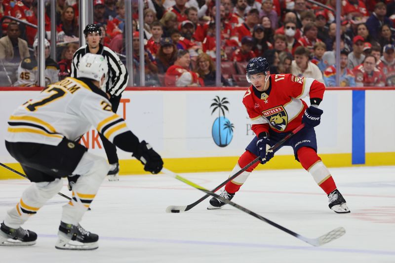 Oct 8, 2024; Sunrise, Florida, USA; Florida Panthers center Evan Rodrigues (17) moves the puck against Boston Bruins defenseman Hampus Lindholm (27) during the second period at Amerant Bank Arena. Mandatory Credit: Sam Navarro-Imagn Images