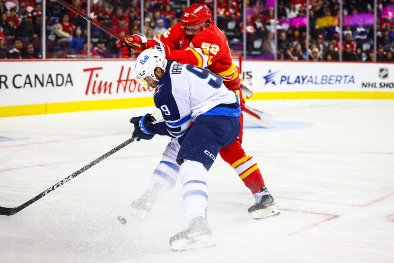 Oct 4, 2024; Calgary, Alberta, CAN; Winnipeg Jets left wing Alex Iafallo (9) and Calgary Flames defenseman MacKenzie Weegar (52) battles for the puck during the third period at Scotiabank Saddledome. Mandatory Credit: Sergei Belski-Imagn Images