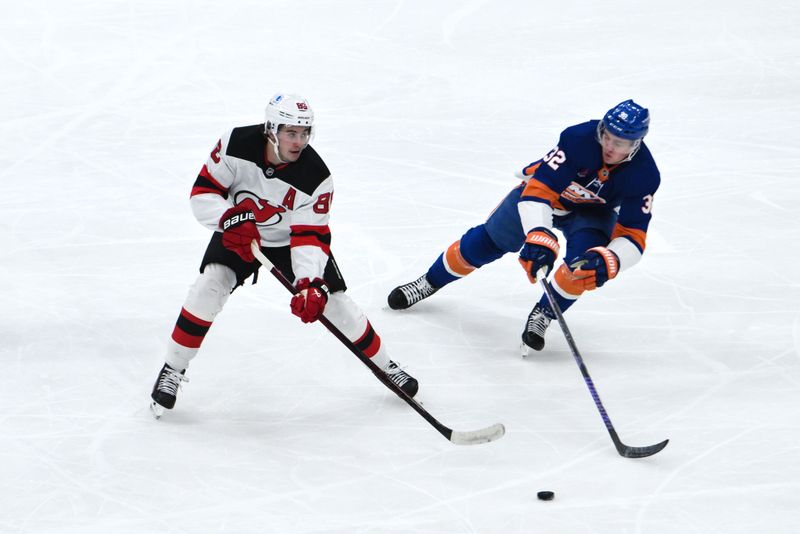 Nov 9, 2024; Elmont, New York, USA; New Jersey Devils center Jack Hughes (86) skates with the puck while being defended by New York Islanders center Kyle MacLean (32) during the first period at UBS Arena. Mandatory Credit: John Jones-Imagn Images