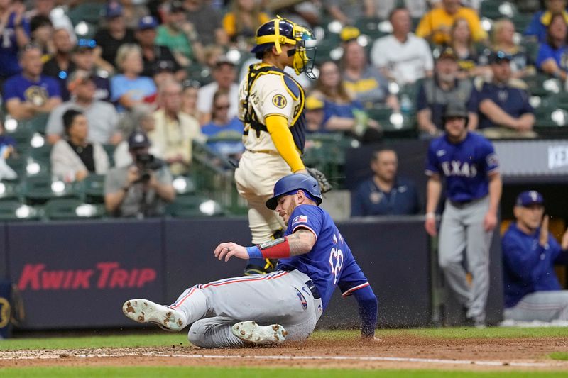 Jun 24, 2024; Milwaukee, Wisconsin, USA;  Texas Rangers catcher Jonah Heim (28) slides into home plate to score a run in front of Milwaukee Brewers designated hitter William Contreras (24) during the fifth inning at American Family Field. Mandatory Credit: Jeff Hanisch-USA TODAY Sports