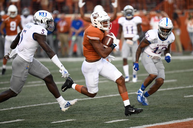 Oct 19, 2019; Austin, TX, USA; Texas Longhorns running back Roschon Johnson (middle) runs in for a touchdown against Kansas Jayhawks linebacker Azur Kamara (5) and safety Jeremiah McCullough (12) in the first half at Darrell K Royal-Texas Memorial Stadium. Mandatory Credit: Scott Wachter-USA TODAY Sports