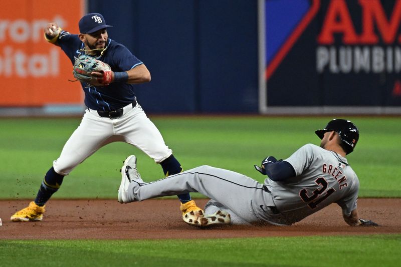 Apr 23, 2024; St. Petersburg, Florida, USA; Tampa Bay Rays shortstop Jose Caballero (left) looks to make a throw to first base as Detroit Tigers designated hitter Riley Greene (31) slides in the first inning at Tropicana Field. Mandatory Credit: Jonathan Dyer-USA TODAY Sports