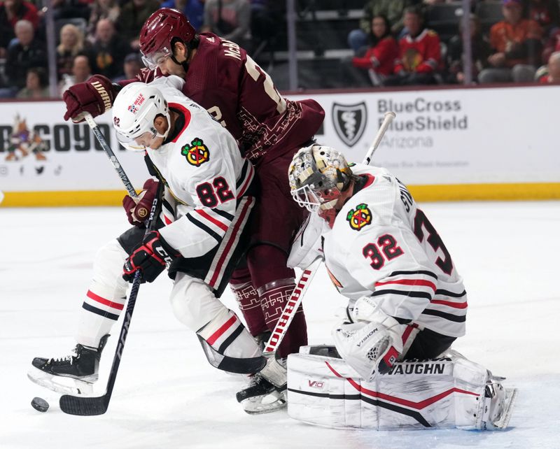 Mar 18, 2023; Tempe, Arizona, USA; Chicago Blackhawks defenseman Caleb Jones (82) and Arizona Coyotes center Jack McBain (22) battle for the puck in front of Chicago Blackhawks goaltender Alex Stalock (32) during the second period at Mullett Arena. Mandatory Credit: Joe Camporeale-USA TODAY Sports