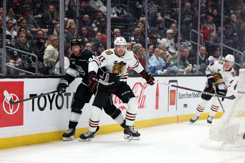 Mar 19, 2024; Los Angeles, California, USA;  Chicago Blackhawks right wing Taylor Raddysh (11) and Los Angeles Kings defenseman Vladislav Gavrikov (84) fight for the puck during the second period at Crypto.com Arena. Mandatory Credit: Kiyoshi Mio-USA TODAY Sports