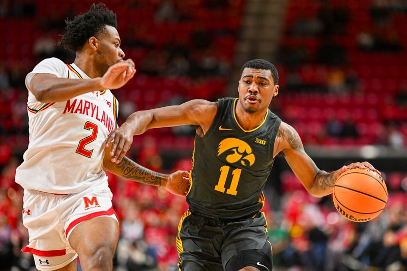 Feb 14, 2024; College Park, Maryland, USA; Iowa Hawkeyes guard Tony Perkins (11) dribbles up the court as Maryland Terrapins guard Jahari Long (2) defends during the fist half  at Xfinity Center. Mandatory Credit: Tommy Gilligan-USA TODAY Sports