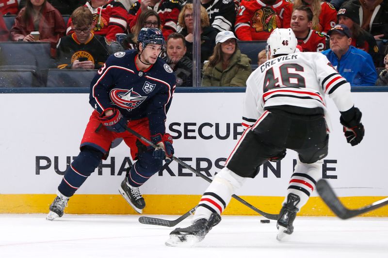 Feb 4, 2026; Columbus, Ohio, USA; Columbus Blue Jackets center Sean Monahan (23) passes the puck as Chicago Blackhawks defenseman Louis Crevier (46) defends during the second period at Nationwide Arena. Mandatory Credit: Russell LaBounty-Imagn Images
