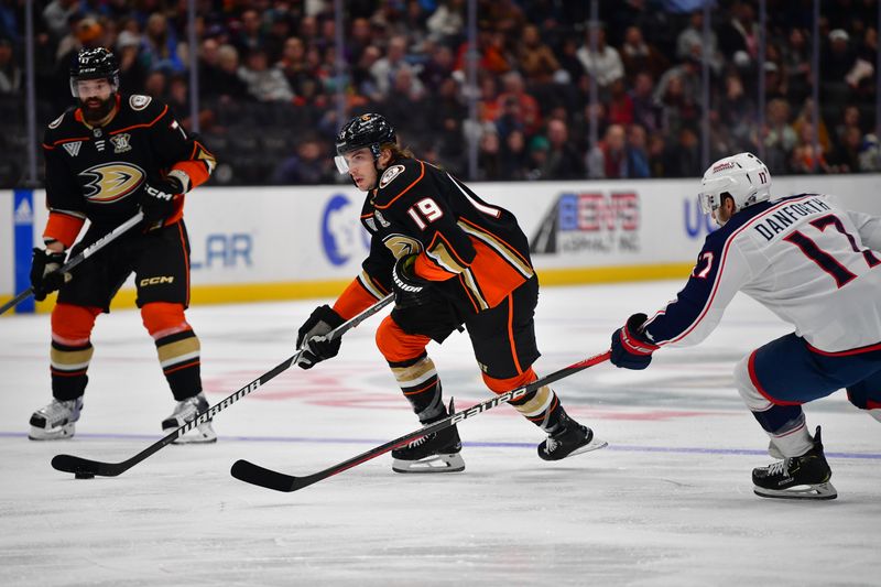 Feb 21, 2024; Anaheim, California, USA; Anaheim Ducks right wing Troy Terry (19) moves the puck against Columbus Blue Jackets right wing Justin Danforth (17) during the third period at Honda Center. Mandatory Credit: Gary A. Vasquez-USA TODAY Sports