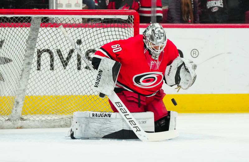 Dec 23, 2023; Raleigh, North Carolina, USA; Carolina Hurricanes goaltender Yaniv Perets (60) stops a shot during the warmups before the game against the New York Islanders at PNC Arena. Mandatory Credit: James Guillory-USA TODAY Sports