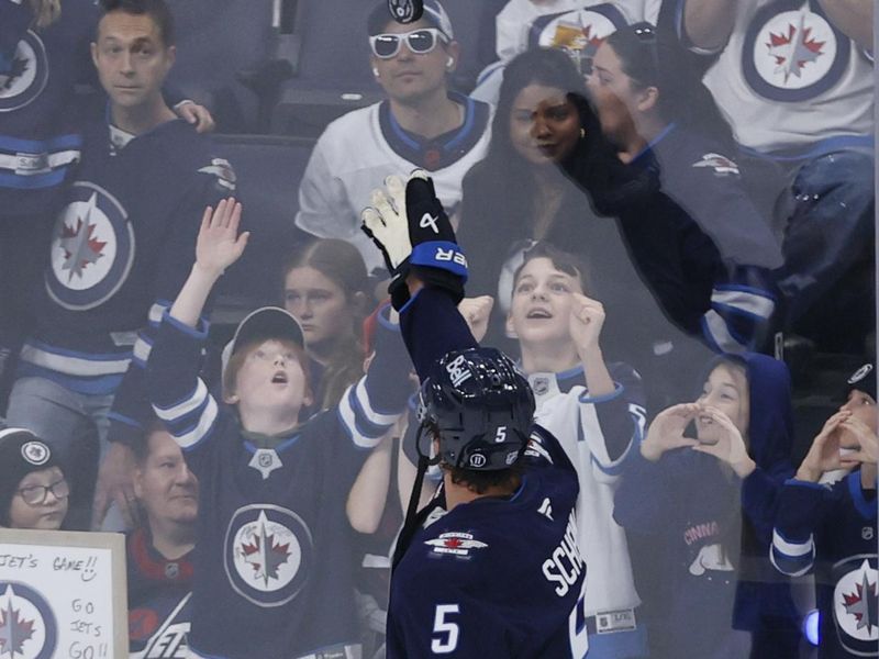 Oct 11, 2025; Winnipeg, Manitoba, CAN; Winnipeg Jets defenseman Luke Schenn (5) tosses a puck to fans before a game against the Los Angeles Kings at Canada Life Centre. Mandatory Credit: James Carey Lauder-Imagn Images