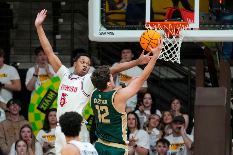 Jan 27, 2024; Laramie, Wyoming, USA; Colorado State Rams forward Patrick Cartier (12) shoots against Wyoming Cowboys forward Cam Manyawu (5) during overtime at Arena-Auditorium. Mandatory Credit: Troy Babbitt-USA TODAY Sports