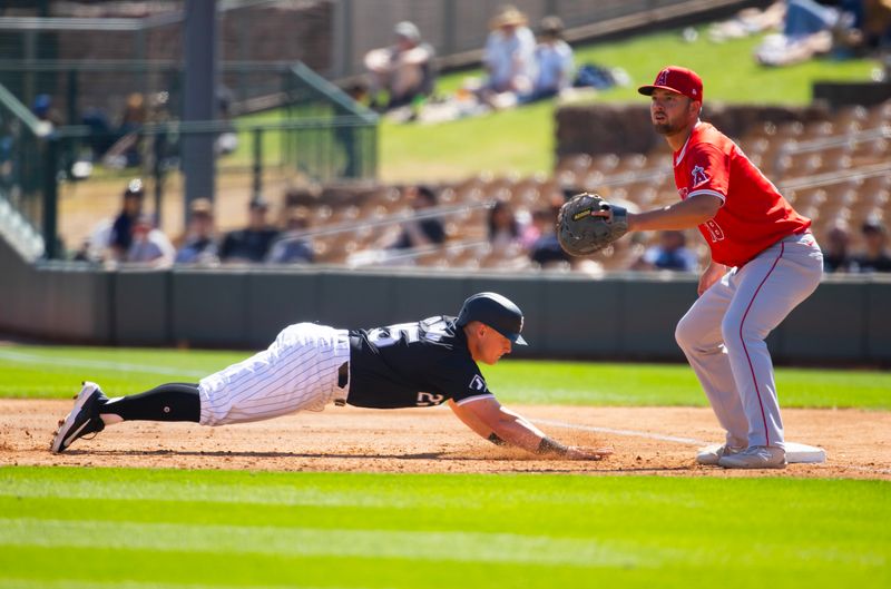 Mar 14, 2024; Phoenix, Arizona, USA; Chicago White Sox base runner Andrew Vaughn dives back to first base as Los Angeles Angels first baseman Nolan Schanuel waits for the ball during a spring training baseball game at Camelback Ranch-Glendale. Mandatory Credit: Mark J. Rebilas-USA TODAY Sports