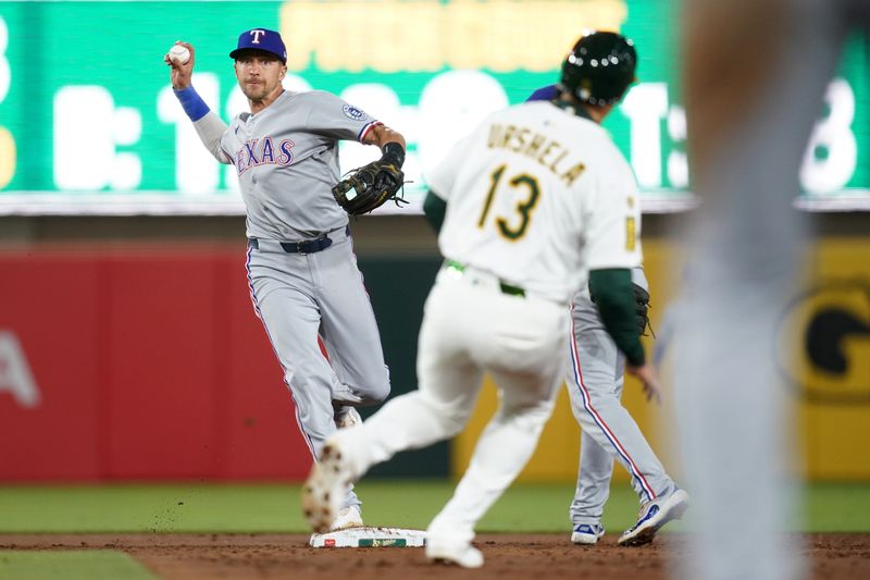 Apr 23, 2025; West Sacramento, California, USA; Texas Rangers shortstop Nick Ahmed (23) turns a double play in front of Athletics third baseman Gio Urshela (13) in the third inning at Sutter Health Park. Mandatory Credit: Cary Edmondson-Imagn Images