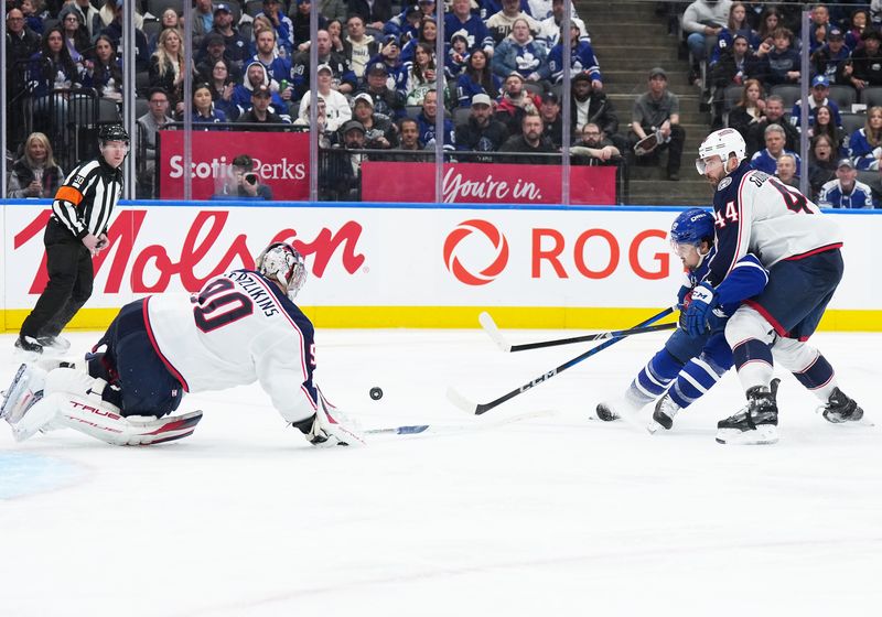 Apr 5, 2025; Toronto, Ontario, CAN; Toronto Maple Leafs left wing Nicholas Robertson (89) battles for the puck with Columbus Blue Jackets defenseman Erik Gudbranson (44) during the third period at Scotiabank Arena. Mandatory Credit: Nick Turchiaro-Imagn Images