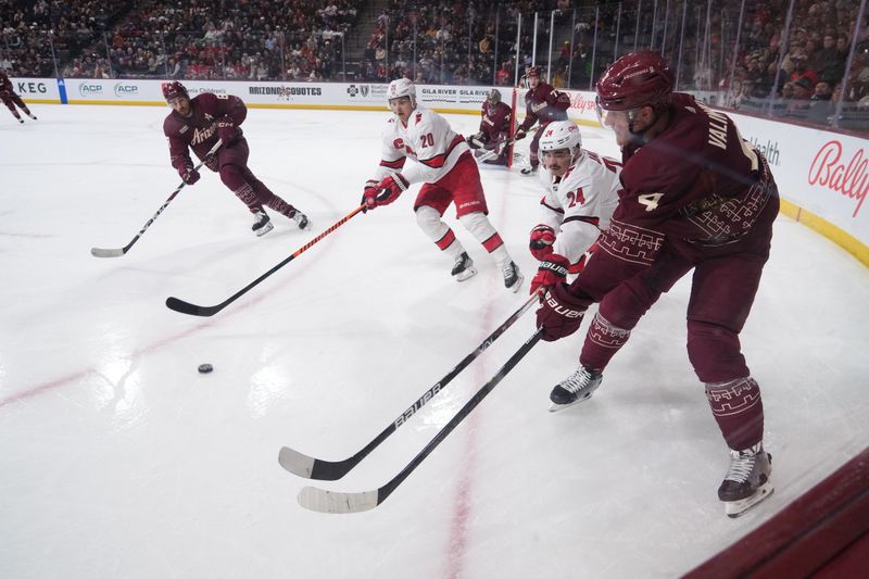 Mar 3, 2023; Tempe, Arizona, USA; Arizona Coyotes defenseman Juuso Valimaki (4) passes the puck by Carolina Hurricanes center Seth Jarvis (24) during the first period at Mullett Arena. Mandatory Credit: Joe Camporeale-USA TODAY Sports