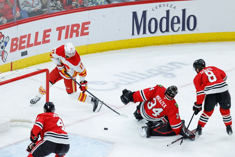 Jan 13, 2025; Chicago, Illinois, USA; Calgary Flames center Yegor Sharangovich (17) scores a goal past Chicago Blackhawks goaltender Petr Mrazek (34) during the second period at United Center. Mandatory Credit: Kamil Krzaczynski-Imagn Images