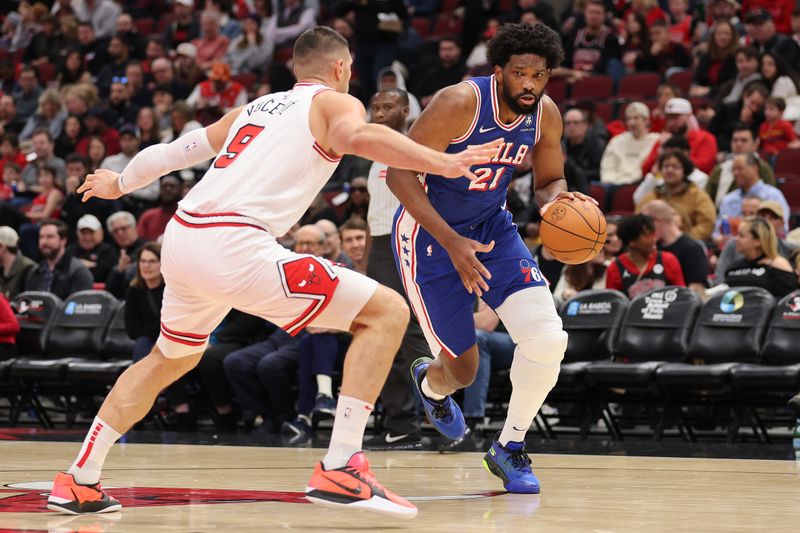 CHICAGO, ILLINOIS - DECEMBER 08: Joel Embiid #21 of the Philadelphia 76ers drives to the basket against Nikola Vucevic #9 of the Chicago Bulls during the first half at the United Center on December 08, 2024 in Chicago, Illinois. NOTE TO USER: User expressly acknowledges and agrees that, by downloading and or using this photograph, User is consenting to the terms and conditions of the Getty Images License Agreement.  (Photo by Michael Reaves/Getty Images)