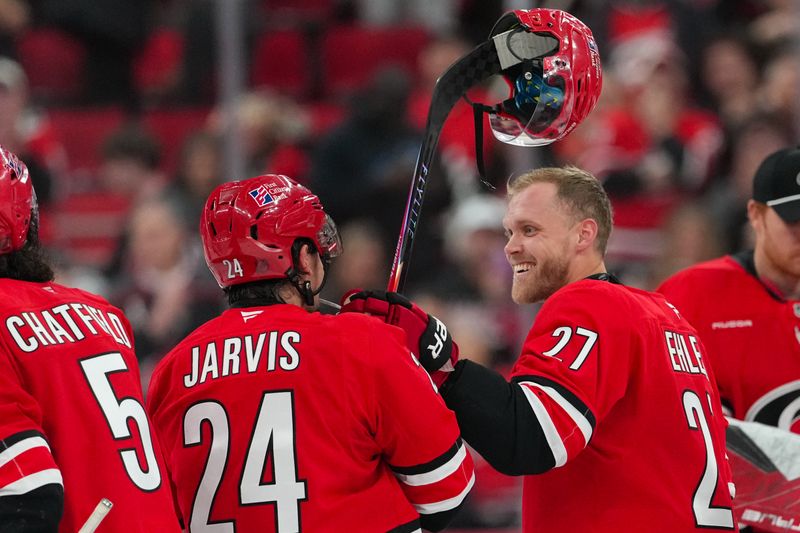 Nov 30, 2025; Raleigh, North Carolina, USA;  Carolina Hurricanes left wing Nikolaj Ehlers (27) and center Seth Jarvis (24) celebrate their victory against the Calgary Flames in the over time at Lenovo Center. Mandatory Credit: James Guillory-Imagn Images
