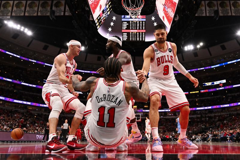 CHICAGO, ILLINOIS - APRIL 02:  DeMar DeRozan #11 of the Chicago Bulls is helped up by teammates Alex Caruso #6, Patrick Beverley #21 and Nikola Vucevic #9 after drawing a foul in the second half against the Memphis Grizzlies on April 02, 2023 at United Center in Chicago, Illinois. Chicago defeated Memphis 128-107.   NOTE TO USER: User expressly acknowledges and agrees that, by downloading and or using this photograph, User is consenting to the terms and conditions of the Getty Images License Agreement.  (Photo by Jamie Sabau/Getty Images)