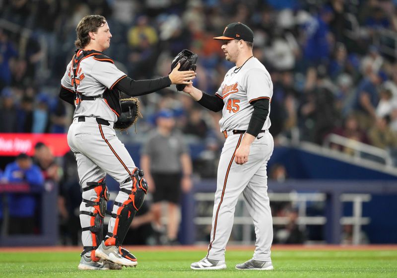 Jun 3, 2024; Toronto, Ontario, CAN; Baltimore Orioles catcher Adley Rutschman (35) and relief pitcher Keegan Akin (45) celebrate the win against the Toronto Blue Jaysat the end of the ninth inning at Rogers Centre. Mandatory Credit: Nick Turchiaro-USA TODAY Sports