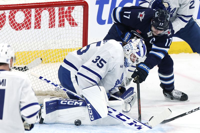 Jan 17, 2026; Winnipeg, Manitoba, CAN; Toronto Maple Leafs goaltender Dennis Hildeby (35) stops a shot from Winnipeg Jets center Adam Lowry (17) in the first period at Canada Life Centre. Mandatory Credit: James Carey Lauder-Imagn Images