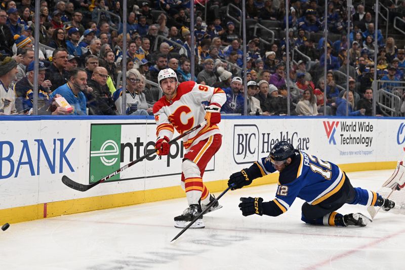 Jan 16, 2025; St. Louis, Missouri, USA; St. Louis Blues center Radek Faksa (12) falls to the ice while Calgary Flames defenseman Brayden Pachal (94) makes a pass in the second period at Enterprise Center. Mandatory Credit: Joe Puetz-Imagn Images