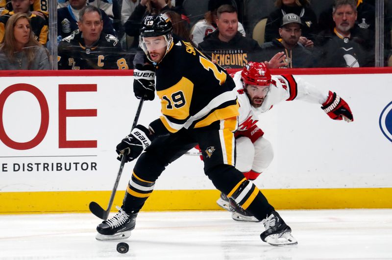 Mar 26, 2024; Pittsburgh, Pennsylvania, USA; Pittsburgh Penguins right wing Reilly Smith (19) moves the puck against Carolina Hurricanes left wing Jordan Martinook (48) during the first period at PPG Paints Arena. Mandatory Credit: Charles LeClaire-USA TODAY Sports