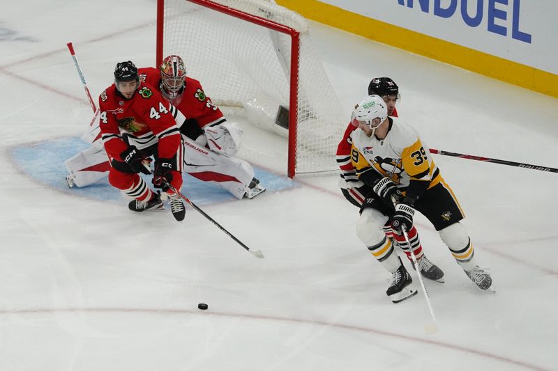 Dec 28, 2025; Chicago, Illinois, USA; Chicago Blackhawks defenseman Wyatt Kaiser (44) and Pittsburgh Penguins right wing Anthony Mantha (39) reach for the puck during the first period at United Center. Mandatory Credit: David Banks-Imagn Images