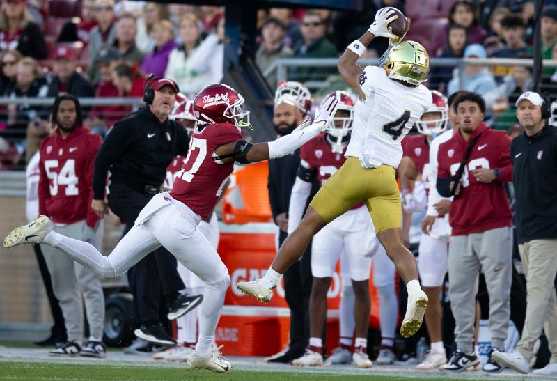 Nov 25, 2023; Stanford, California, USA; Notre Dame Fighting Irish wide receiver Chris Tyree (4) hauls in a long pass over Stanford Cardinal safety Omari Porter (27) during the first quarter at Stanford Stadium. Mandatory Credit: D. Ross Cameron-USA TODAY Sports