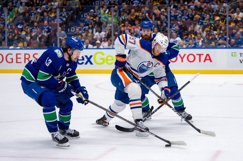 May 20, 2024; Vancouver, British Columbia, CAN; Vancouver Canucks defenseman Quinn Hughes (43) strips Edmonton Oilers forward Connor McDavid (97) of the puck as defenseman Filip Hronek (17) watches during the second period in game seven of the second round of the 2024 Stanley Cup Playoffs at Rogers Arena. Mandatory Credit: Bob Frid-USA TODAY Sports