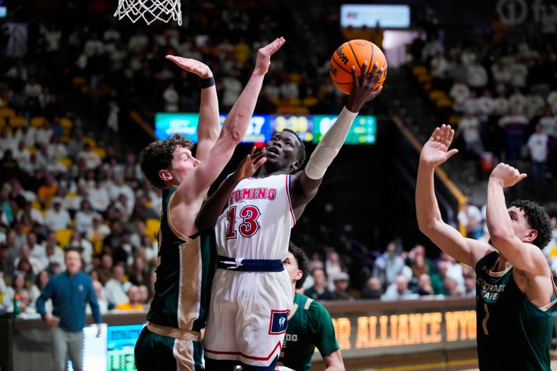 Jan 27, 2024; Laramie, Wyoming, USA; Wyoming Cowboys guard Akuel Kot (13) shoots against Colorado State Rams forward Patrick Cartier (12) during overtime at Arena-Auditorium. Mandatory Credit: Troy Babbitt-USA TODAY Sports