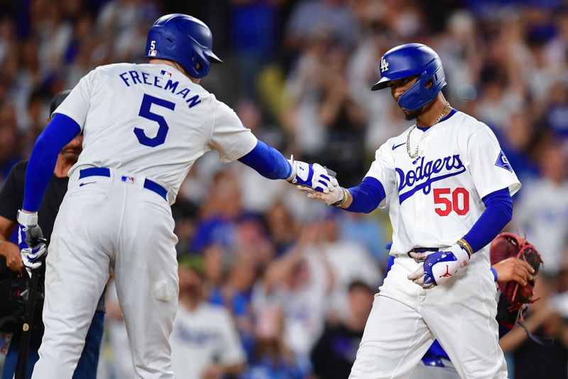 Sep 9, 2024; Los Angeles, California, USA; Los Angeles Dodgers right fielder Mookie Betts (50) is greeted by first baseman Freddie Freeman (5) after hitting a two run home run against the Chicago Cubs during the seventh inning at Dodger Stadium. Mandatory Credit: Gary A. Vasquez-Imagn Images