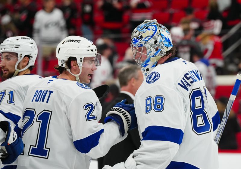 Oct 11, 2024; Raleigh, North Carolina, USA;  Tampa Bay Lightning goaltender Andrei Vasilevskiy (88) and center Brayden Point (21) celebrate their victory against the Carolina Hurricanes at PNC Arena. Mandatory Credit: James Guillory-Imagn Images