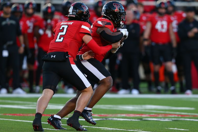 Nov 2, 2023; Lubbock, Texas, USA; Texas Tech Red Raiders quarterback Behren Morton (2) hands the ball in the first half to running back Tahj Brooks (28) during the game against the Texas Christian Horned Frogs at Jones AT&T Stadium and Cody Campbell Field. Mandatory Credit: Michael C. Johnson-USA TODAY Sports