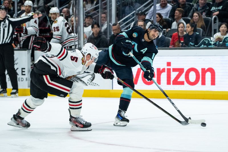 Nov 14, 2024; Seattle, Washington, USA;  Seattle Kraken forward Matty Beniers (10) shoots the puck against Chicago Blackhawks defenseman Connor Murphy (5) during the first period at Climate Pledge Arena. Mandatory Credit: Stephen Brashear-Imagn Images