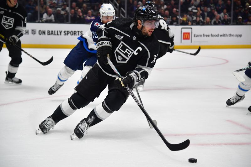 Dec 13, 2023; Los Angeles, California, USA; Los Angeles Kings center Anze Kopitar (11) moves the puck against the Winnipeg Jets during the first period at Crypto.com Arena. Mandatory Credit: Gary A. Vasquez-USA TODAY Sports