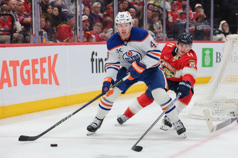 Nov 22, 2025; Sunrise, Florida, USA; Edmonton Oilers defenseman Ty Emberson (49) moves the puck against Florida Panthers right wing Mackie Samoskevich (11) during the second period at Amerant Bank Arena. Mandatory Credit: Sam Navarro-Imagn Images