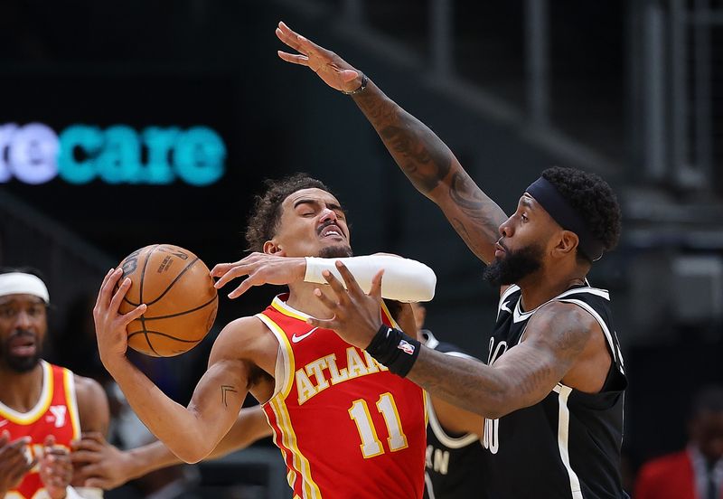 ATLANTA, GEORGIA - DECEMBER 06:  Mikal Bridges #1 of the Brooklyn Nets drives between Onyeka Okongwu #17 and Bogdan Bogdanovic #13 of the Atlanta Hawks during the third quarter at State Farm Arena on December 06, 2023 in Atlanta, Georgia.  NOTE TO USER: User expressly acknowledges and agrees that, by downloading and/or using this photograph, user is consenting to the terms and conditions of the Getty Images License Agreement.  (Photo by Kevin C. Cox/Getty Images)