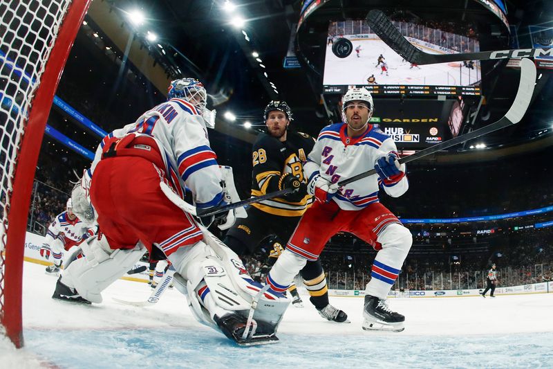 Nov 28, 2025; Boston, Massachusetts, USA; New York Rangers goaltender Igor Shesterkin (31), defenseman Matthew Robertson (29) and Boston Bruins center Elias Lindholm (28) all eye a loose puck in the crease during the third period at TD Garden. Mandatory Credit: Winslow Townson-Imagn Images