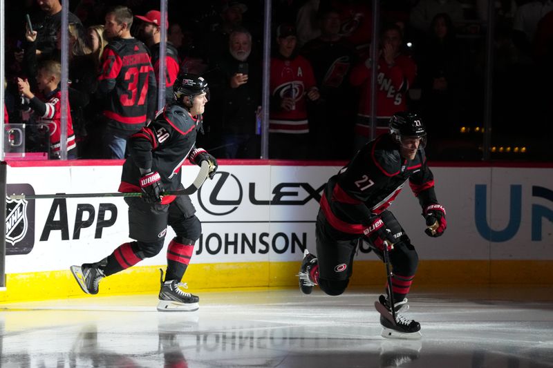 Oct 11, 2025; Raleigh, North Carolina, USA;  Carolina Hurricanes left wing Nikolaj Ehlers (27) and left wing Eric Robinson (50) skate out onto the ice before the start of the game against the Philadelphia Flyers at Lenovo Center. Mandatory Credit: James Guillory-Imagn Images