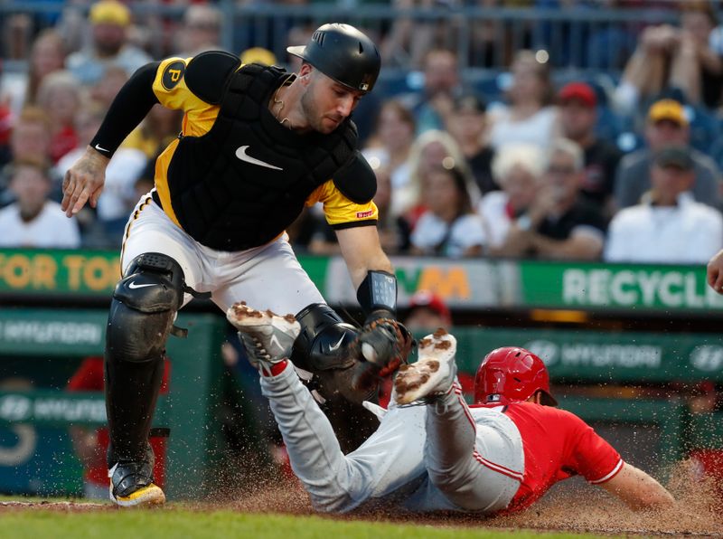 Aug 23, 2024; Pittsburgh, Pennsylvania, USA;  Cincinnati Reds left fielder Spencer Steer (right) slides home to score a run on a suicide squeeze past the tag attempt of Pittsburgh Pirates catcher Joey Bart (14) during the fourth inning at PNC Park. Mandatory Credit: Charles LeClaire-USA TODAY Sports