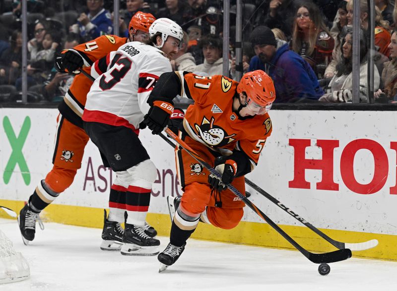 Dec 1, 2024; Anaheim, California, USA;  Anaheim Ducks defenseman Olen Zellweger (51) takes the puck away from Ottawa Senators left wing Noah Gregor (73), defended with left wing Ross Johnston (44) during the third period at Honda Center. Mandatory Credit: Alex Gallardo-Imagn Images