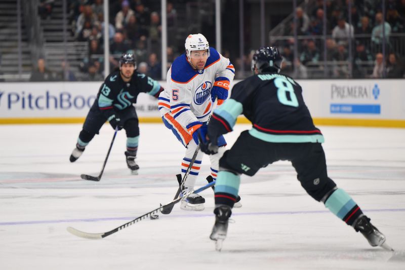 Mar 2, 2024; Seattle, Washington, USA; Edmonton Oilers defenseman Cody Ceci (5) plays the puck while defended by Seattle Kraken defenseman Brian Dumoulin (8) during the first period at Climate Pledge Arena. Mandatory Credit: Steven Bisig-USA TODAY Sports